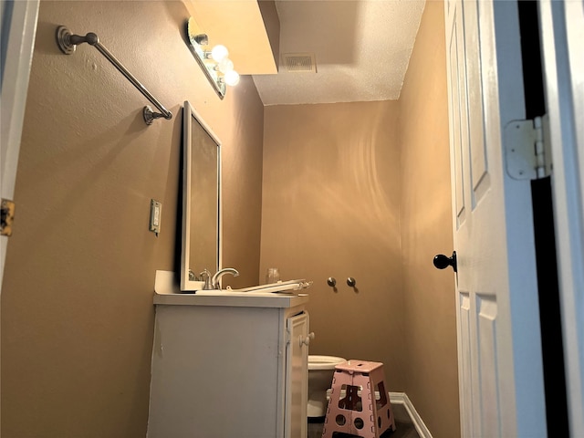 bathroom featuring a textured ceiling, vanity, and toilet