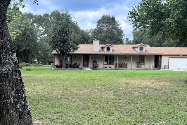 view of front of property featuring covered porch, an attached garage, a chimney, and a front lawn