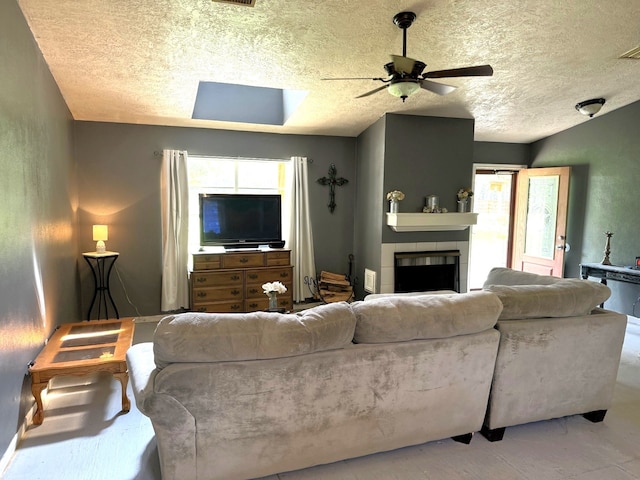 living room with ceiling fan, a textured ceiling, a fireplace, and a healthy amount of sunlight