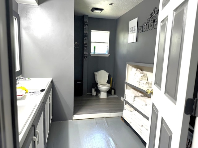 bathroom with vanity, toilet, and a textured ceiling