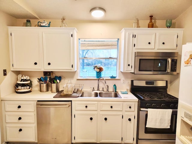 kitchen with appliances with stainless steel finishes, a sink, and white cabinetry