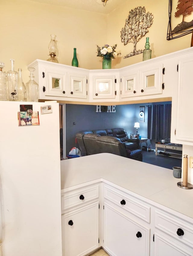 kitchen with white cabinets, light countertops, and freestanding refrigerator