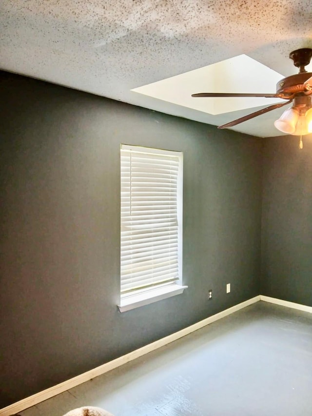 spare room featuring concrete floors, a ceiling fan, and baseboards