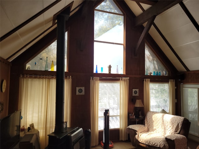 living room featuring vaulted ceiling with beams, plenty of natural light, and wood walls