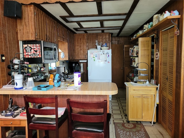 kitchen featuring a kitchen bar, white fridge, and kitchen peninsula