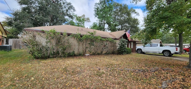 view of side of property with central AC unit and a lawn