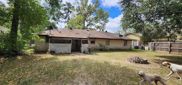 back of house with a lawn and a fire pit