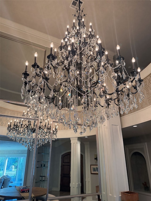 interior details with ornamental molding, decorative columns, and an inviting chandelier