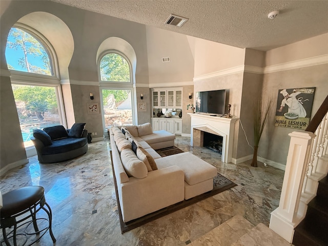 living room featuring a high ceiling, a textured ceiling, and built in shelves