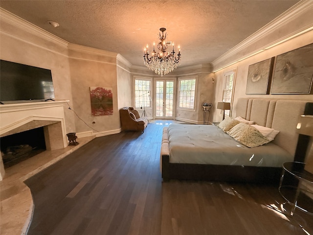 bedroom featuring a textured ceiling, dark hardwood / wood-style floors, a fireplace, an inviting chandelier, and ornamental molding