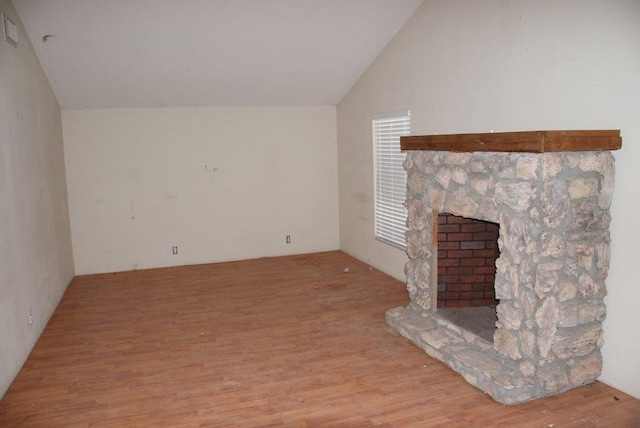 unfurnished living room featuring vaulted ceiling, a fireplace, and light hardwood / wood-style floors