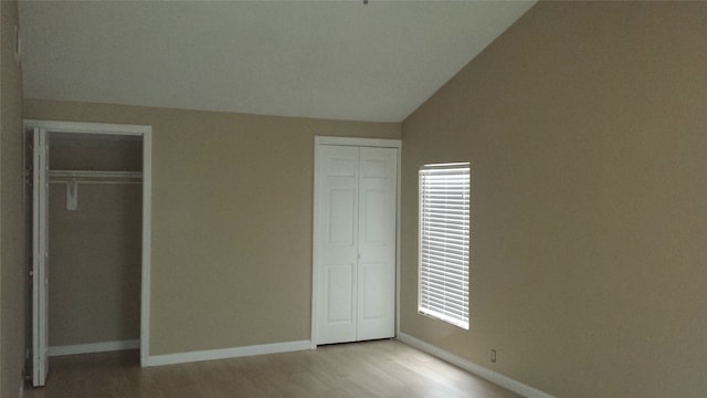 unfurnished bedroom with light hardwood / wood-style floors and lofted ceiling