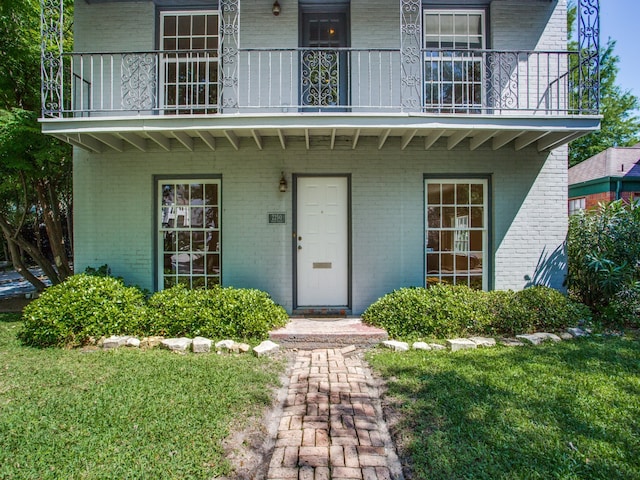 entrance to property with a balcony and a lawn