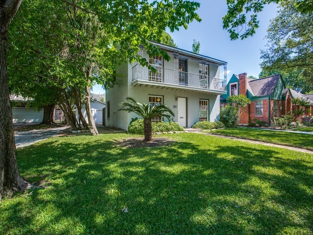 view of front of house featuring a balcony, a front lawn, and a garage