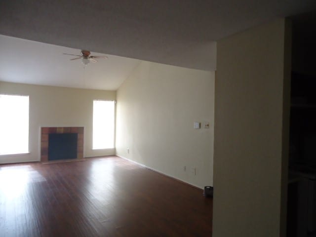 unfurnished living room featuring ceiling fan, a tiled fireplace, and hardwood / wood-style floors