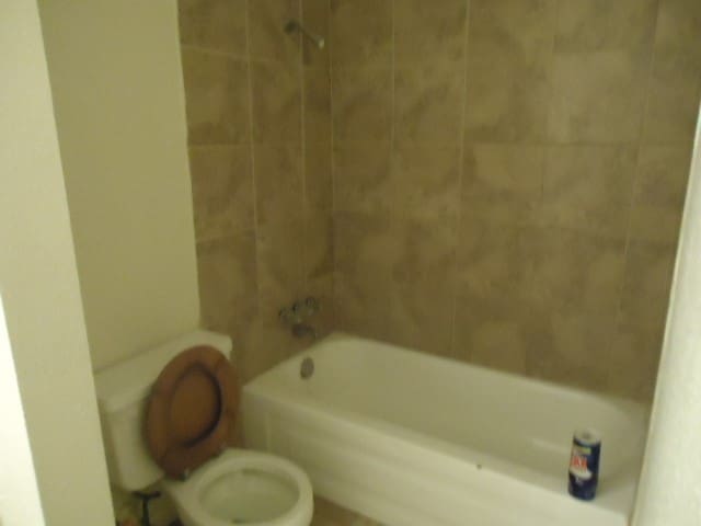 bathroom with toilet and tiled shower / bath