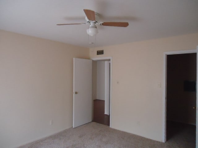 interior space featuring a spacious closet, ceiling fan, and light colored carpet