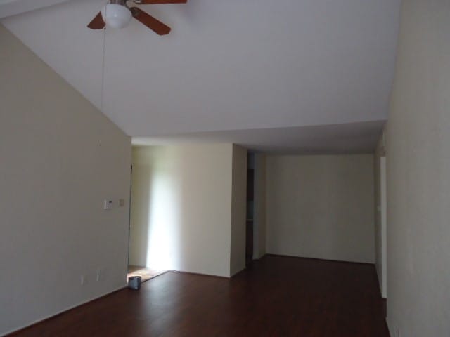 spare room featuring vaulted ceiling, ceiling fan, and dark wood-type flooring