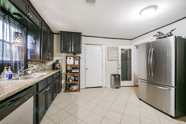 kitchen with light stone counters, appliances with stainless steel finishes, light tile patterned floors, decorative backsplash, and sink