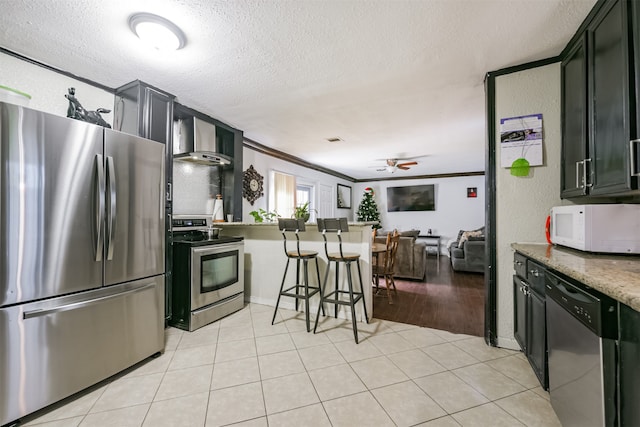 kitchen with ornamental molding, stainless steel appliances, a textured ceiling, and ceiling fan