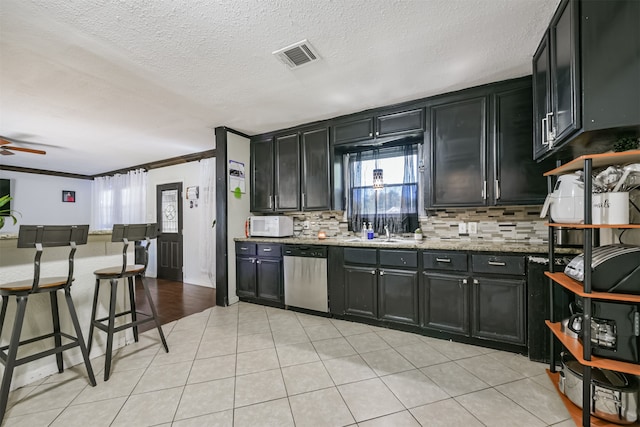 kitchen featuring light stone counters, ceiling fan, crown molding, dishwasher, and decorative backsplash