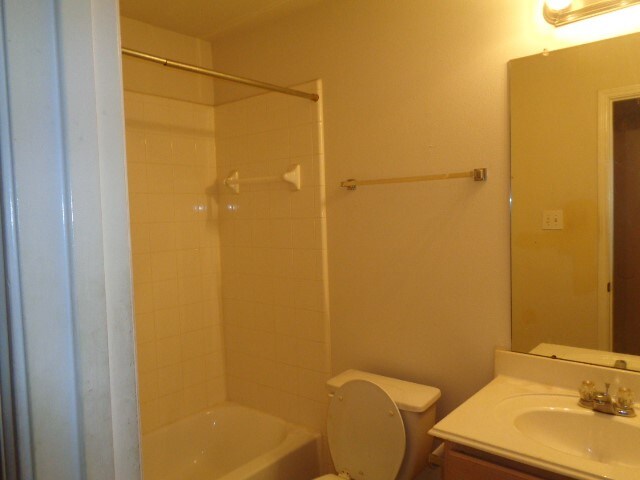 full bathroom featuring vanity, tiled shower / bath combo, and toilet