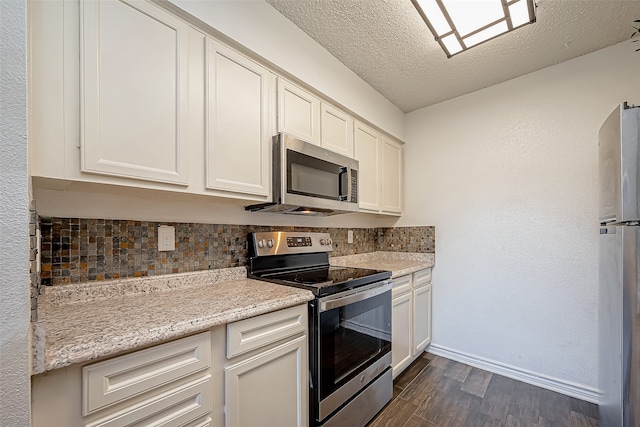 kitchen featuring a textured ceiling, dark hardwood / wood-style floors, decorative backsplash, stainless steel appliances, and light stone countertops