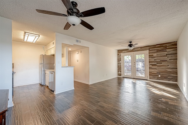 unfurnished living room featuring french doors, a textured ceiling, dark wood-type flooring, and ceiling fan