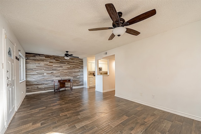 unfurnished living room featuring a textured ceiling, wooden walls, dark hardwood / wood-style floors, and ceiling fan