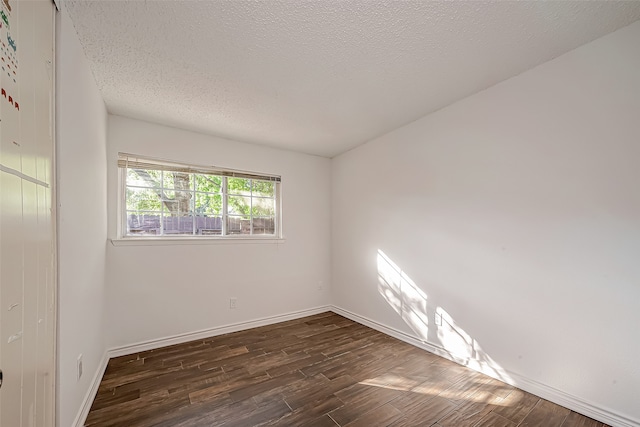 spare room featuring a textured ceiling and dark hardwood / wood-style floors