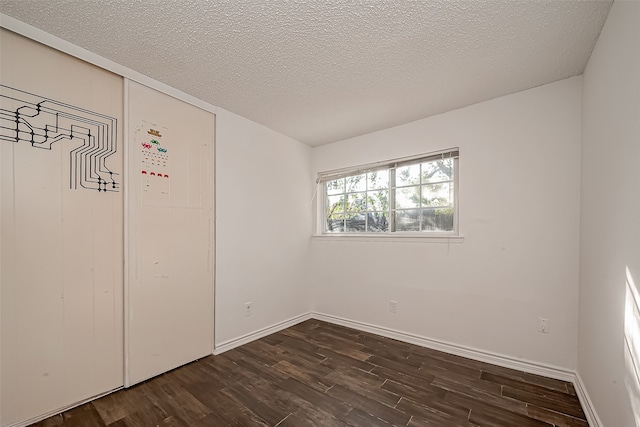 empty room with a textured ceiling and dark wood-type flooring