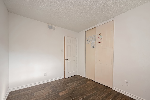 unfurnished room with a textured ceiling and dark hardwood / wood-style flooring