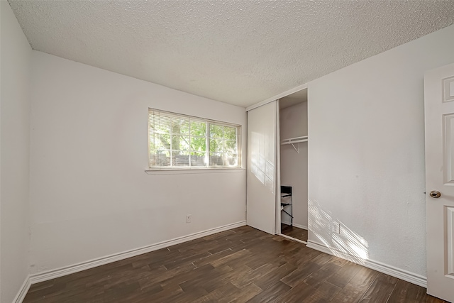 unfurnished bedroom with a textured ceiling, a closet, and dark wood-type flooring