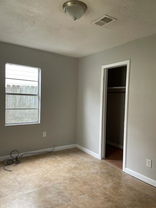 unfurnished bedroom with a textured ceiling, a closet, and a spacious closet