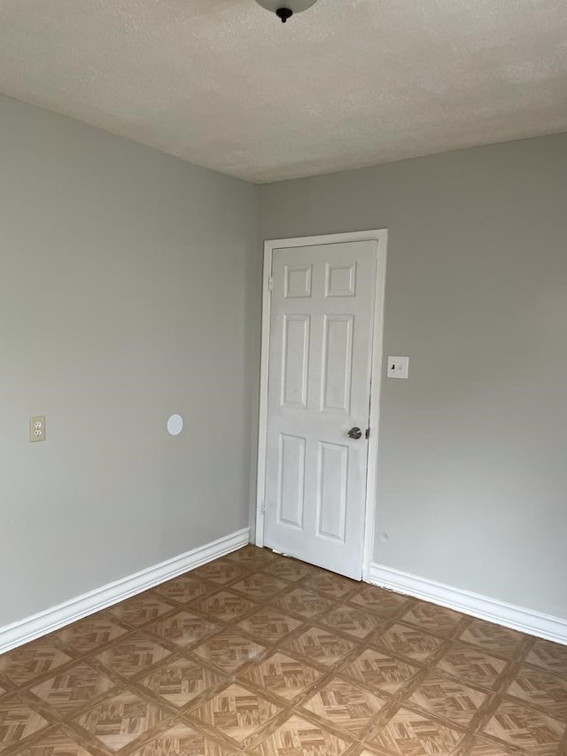 empty room with a textured ceiling and light parquet floors