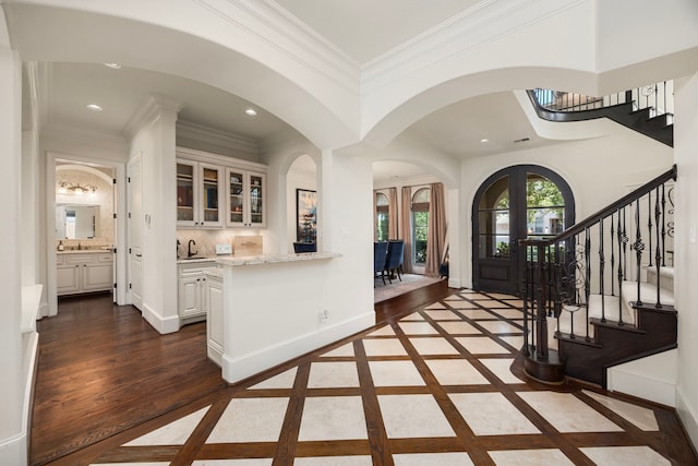 foyer with french doors, sink, crown molding, and dark hardwood / wood-style flooring