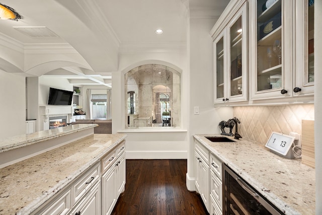 kitchen featuring dark hardwood / wood-style flooring, light stone counters, crown molding, and sink