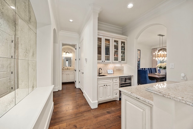 bar with pendant lighting, dark hardwood / wood-style flooring, light stone counters, white cabinetry, and crown molding