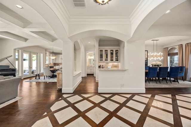 entrance foyer with french doors, a notable chandelier, dark wood-type flooring, and crown molding