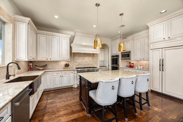 kitchen with premium range hood, sink, dark wood-type flooring, appliances with stainless steel finishes, and a center island