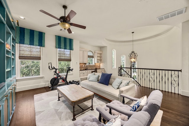 living room featuring ceiling fan with notable chandelier and dark hardwood / wood-style flooring