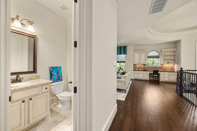 bathroom with tasteful backsplash, hardwood / wood-style flooring, vanity, and toilet