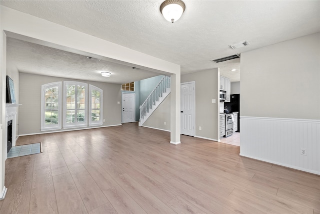 unfurnished living room featuring a textured ceiling and light wood-type flooring