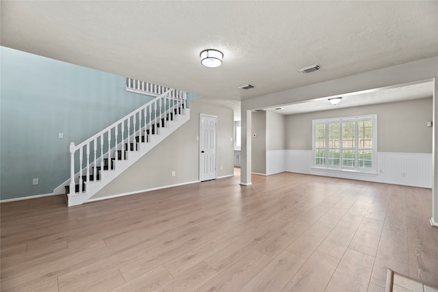 unfurnished living room with a textured ceiling and light hardwood / wood-style floors