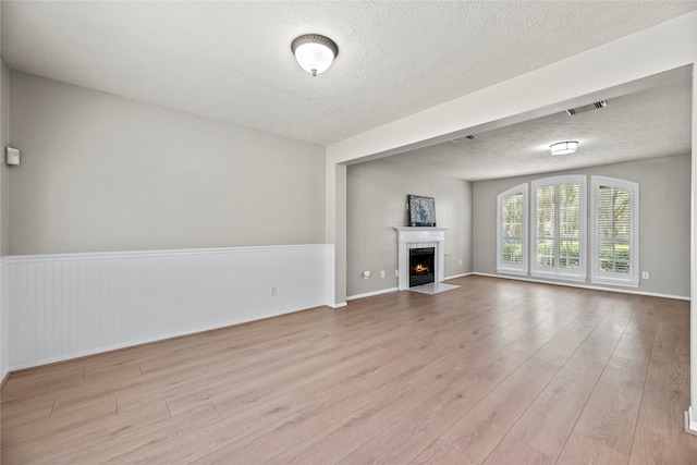 unfurnished living room featuring light hardwood / wood-style floors and a textured ceiling