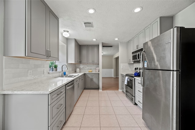 kitchen featuring appliances with stainless steel finishes, a textured ceiling, light tile patterned flooring, and sink