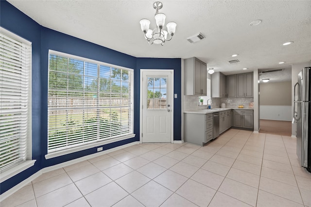 kitchen featuring a textured ceiling, gray cabinetry, light tile patterned floors, and stainless steel appliances