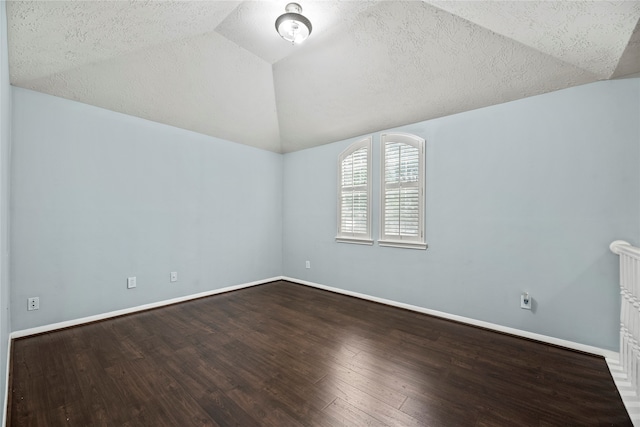 spare room with wood-type flooring, lofted ceiling, and a textured ceiling