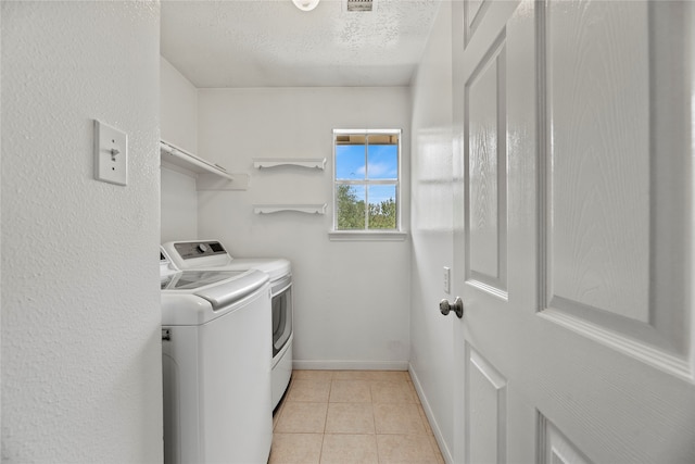 laundry area featuring light tile patterned floors, a textured ceiling, and washer and clothes dryer