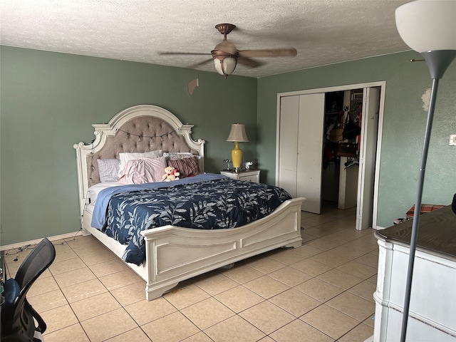 bedroom featuring a textured ceiling, a closet, ceiling fan, and light tile patterned floors